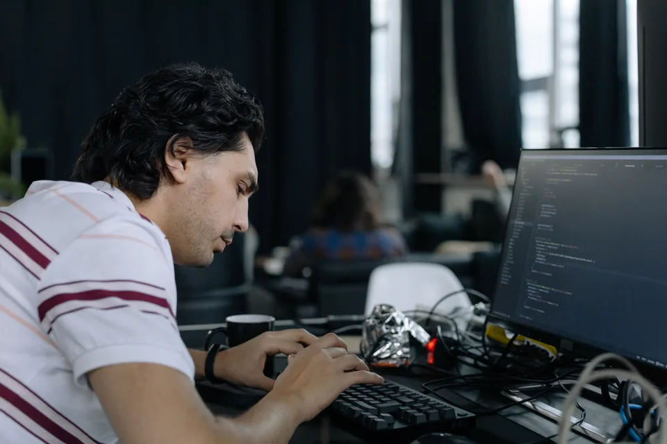 An employee working in an HTML code editor on a computer screen.