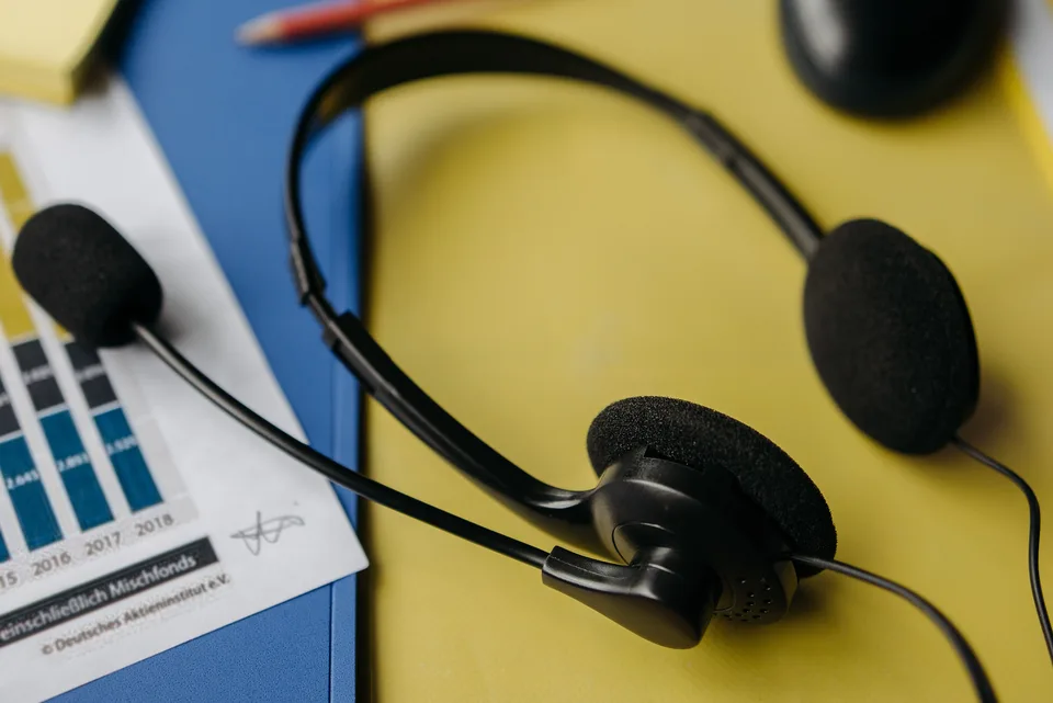 A black headset resting on a yellow file folder in an office workspace.