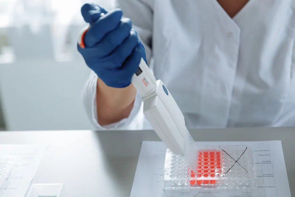 A close-up of a laboratory worker carefully distributing medication into capsules.