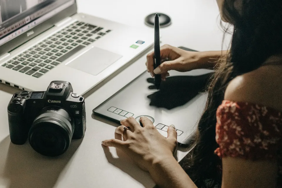 A woman writing and sketching on a digital tablet, working on a creative design project.