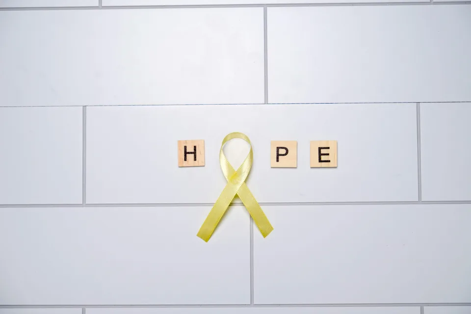 A yellow ribbon symbol on a white tiled surface representing hope and mental health awareness.