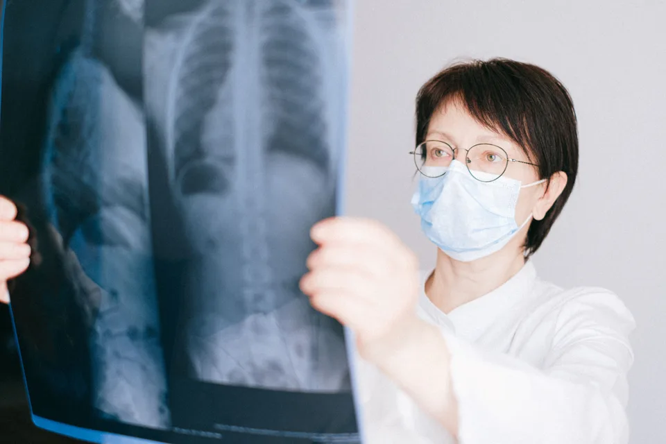A doctor examining an x-ray image on a lightbox in a clinical setting.