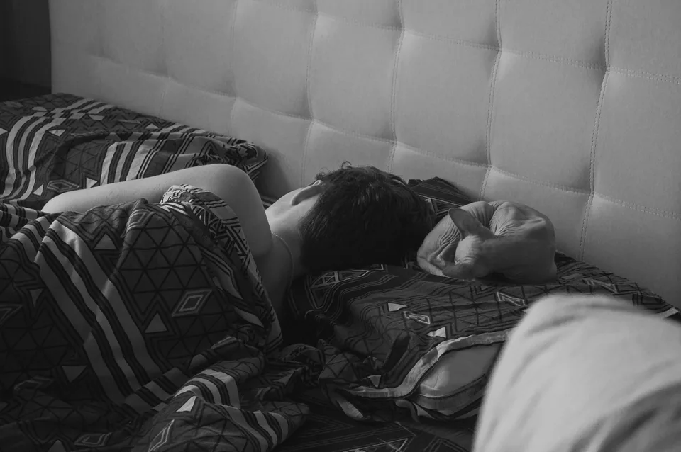 person lying in bed resting in a dim bedroom