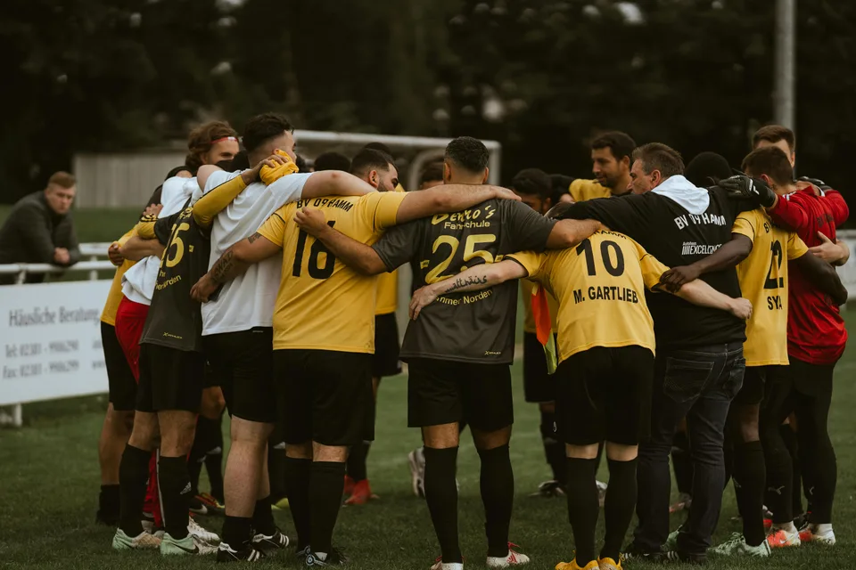 A soccer team huddled together on the field before kickoff.
