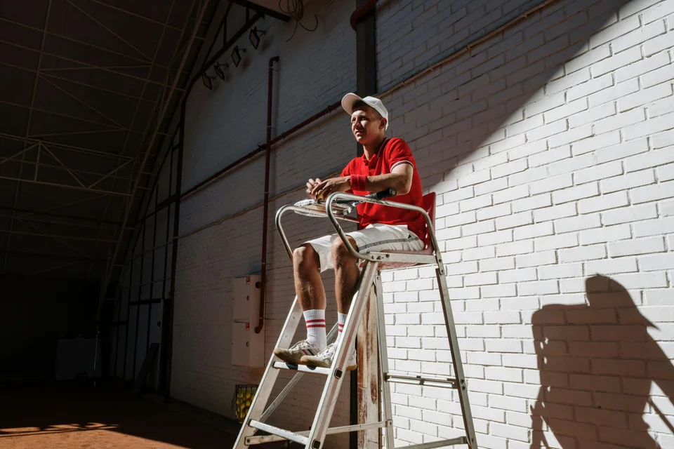 A tennis line judge sitting in an elevated chair watching play on the court.