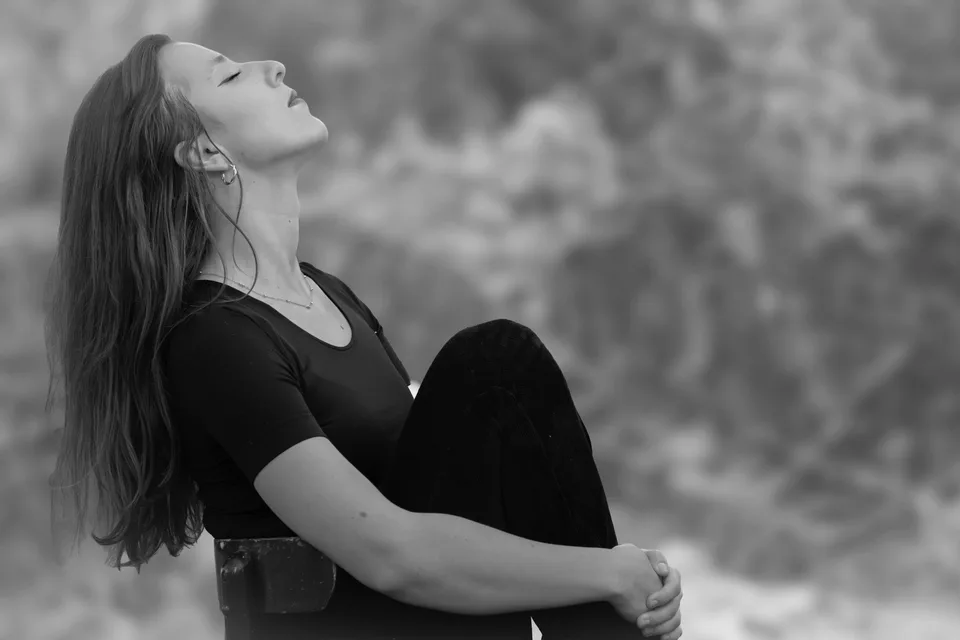 A woman meditating peacefully outdoors surrounded by nature.