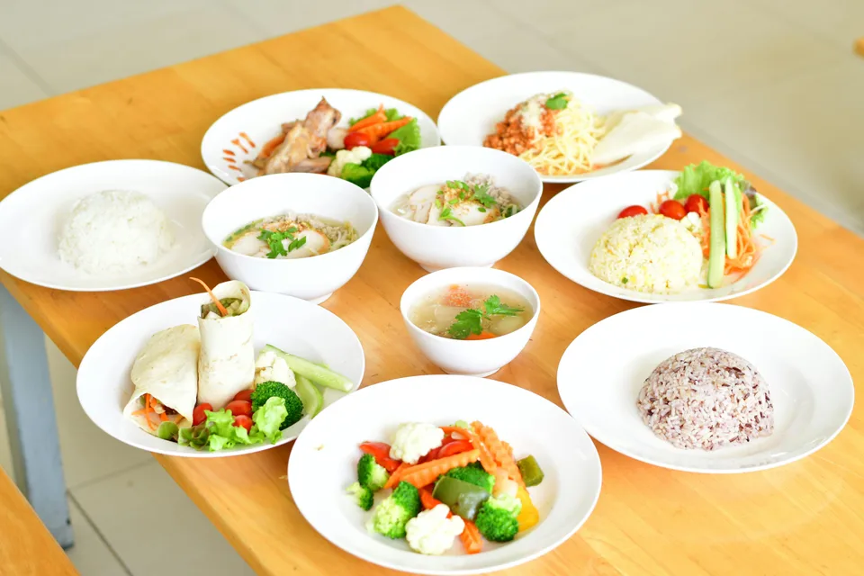 A spread of healthy, colorful, well-prepared meals on a wooden table.