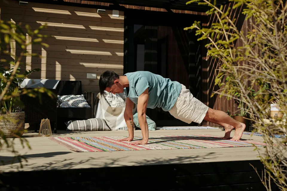 A person working out on a covered outdoor veranda in a calm natural setting.