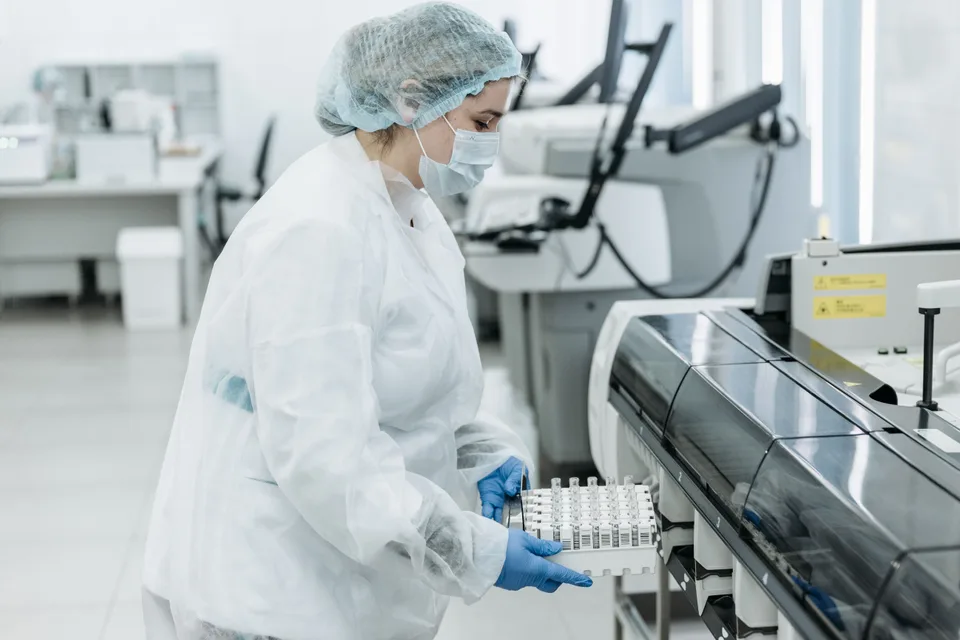 A medical practitioner holding a rack of test tube samples in a laboratory setting.