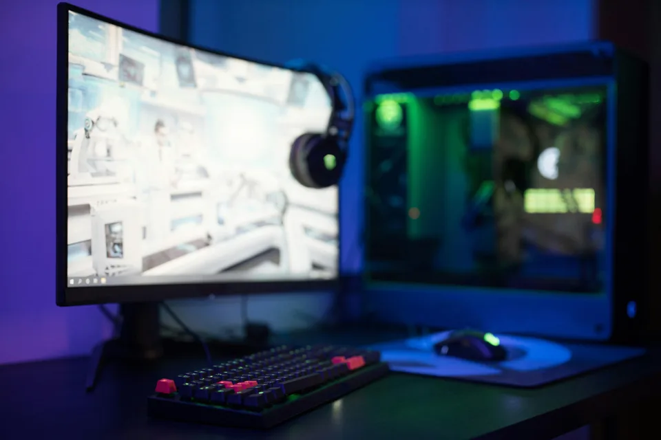A gaming computer with RGB lighting on a desk in a darkened room.
