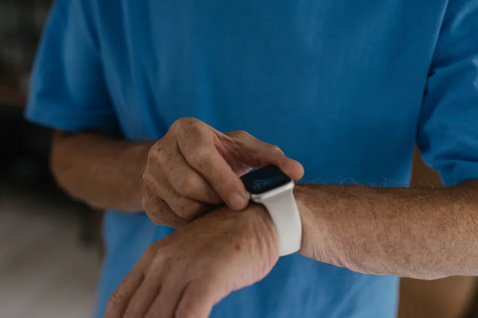 A person wearing a white and black smart watch, showing the device on their wrist.