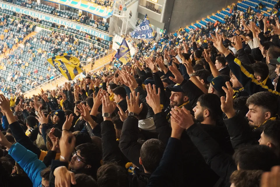 A large cheering crowd at a soccer match inside a packed stadium.