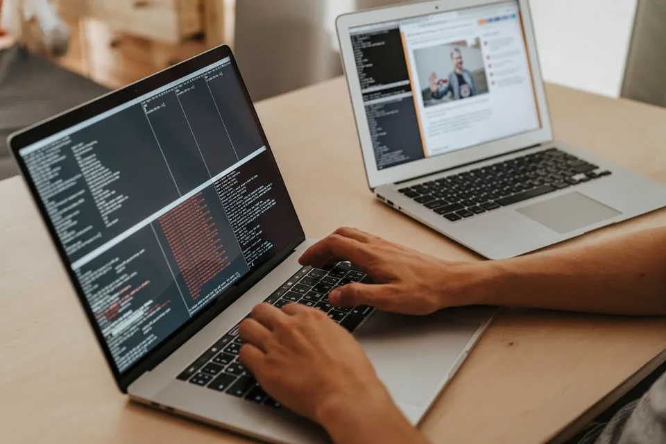 person writing code on a laptop at a desk