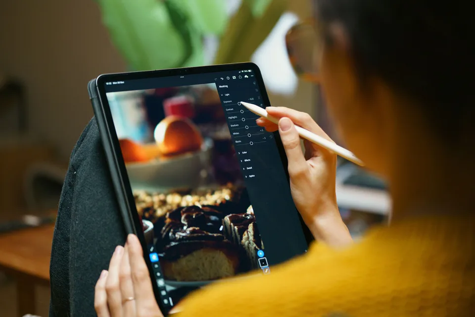 Freelance designer editing photos and videos on a modern tablet in a brightly lit workspace
