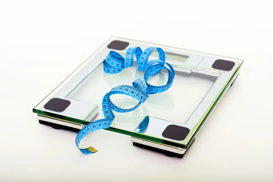 A weighing scale with a blue measuring tape on its surface.