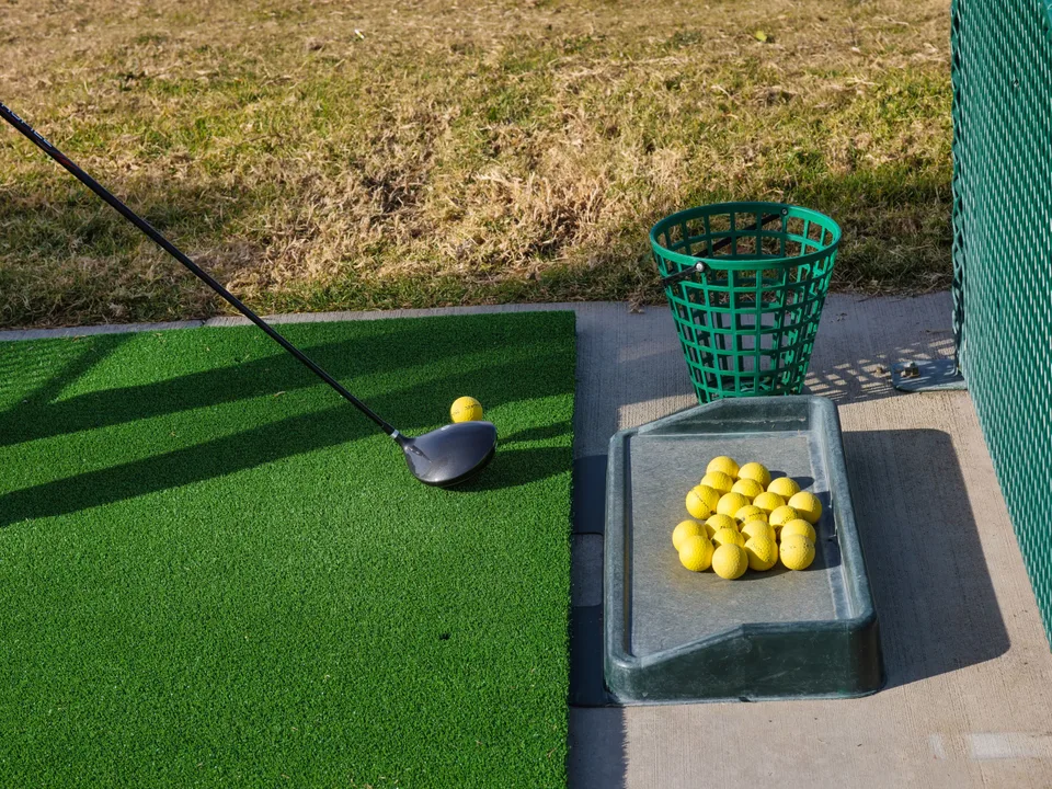 A wide grassy landscape used for outdoor summer recreation and golf practice.
