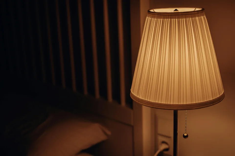 A warm table lamp sits beside an indoor surface in soft warm light.