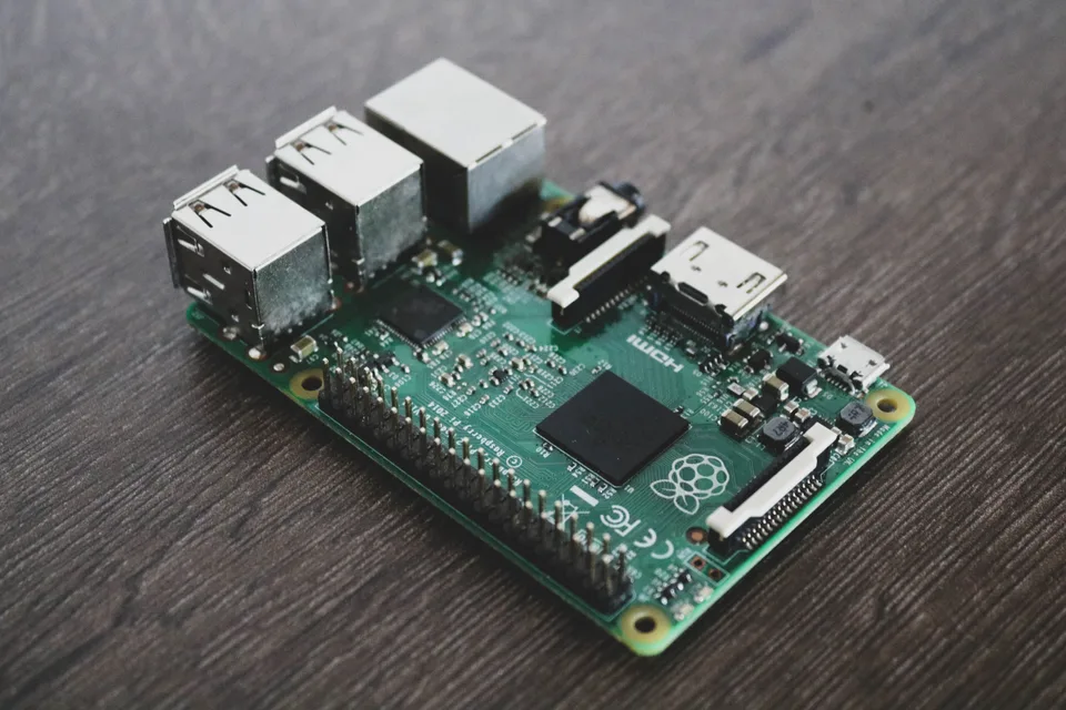 Green Raspberry Pi circuit board with USB and Ethernet ports on a dark wooden desk