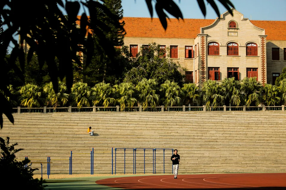 A college athlete running laps on a synthetic running track during practice.