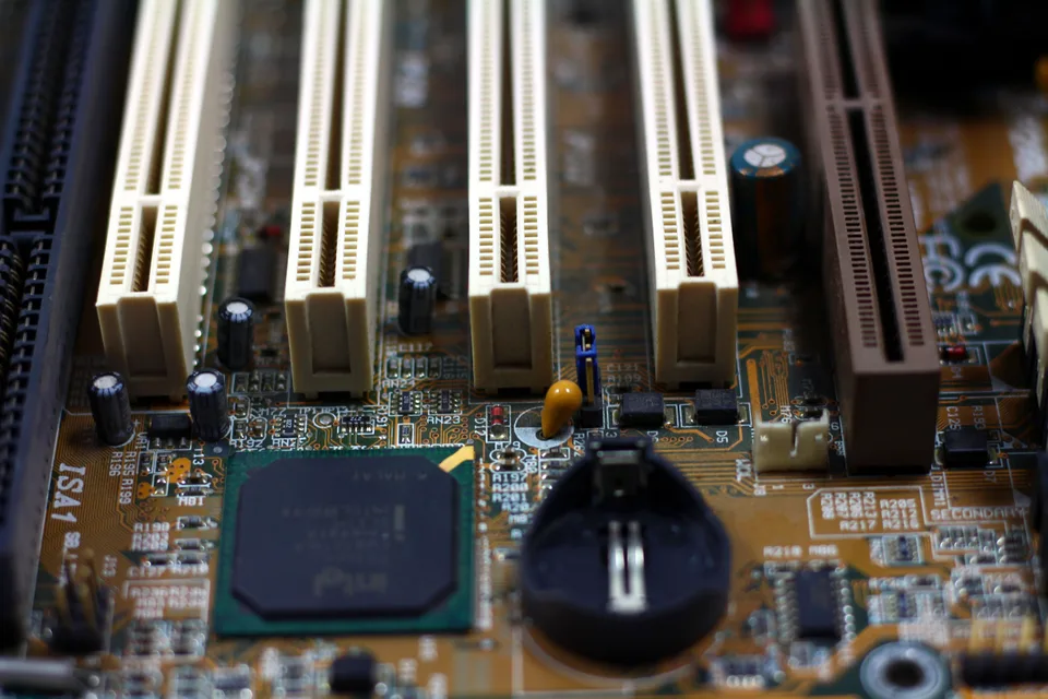A close-up view of a brown motherboard circuit with visible electronic components and pathways.