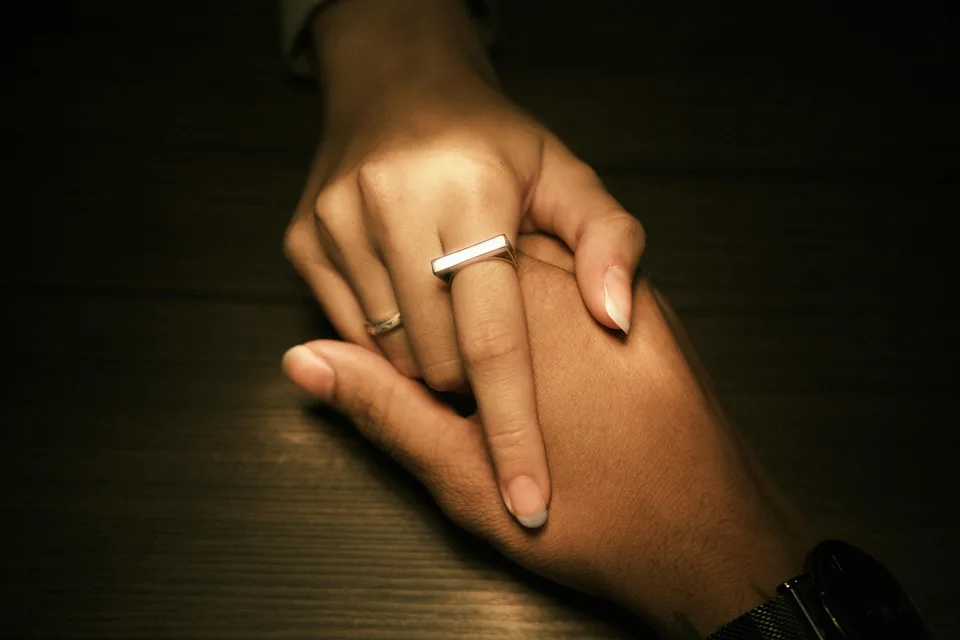 A couple holding hands resting at a wooden table in a calm setting.