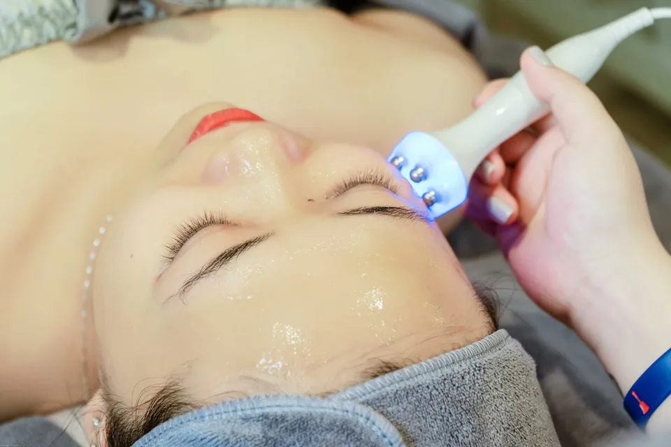 A close-up of a woman receiving an ultrasonic skin treatment in a professional salon setting.