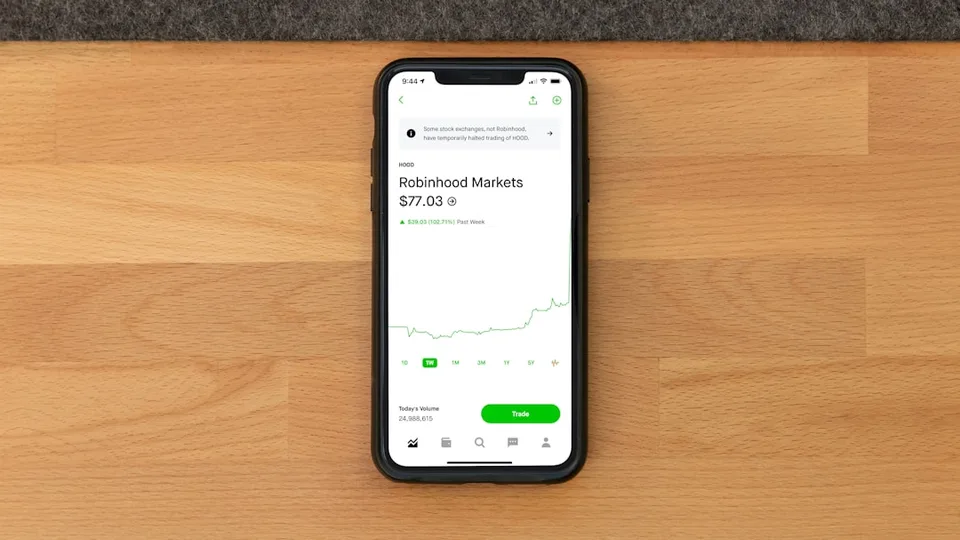a hand holding a smartphone showing the Robinhood trading app