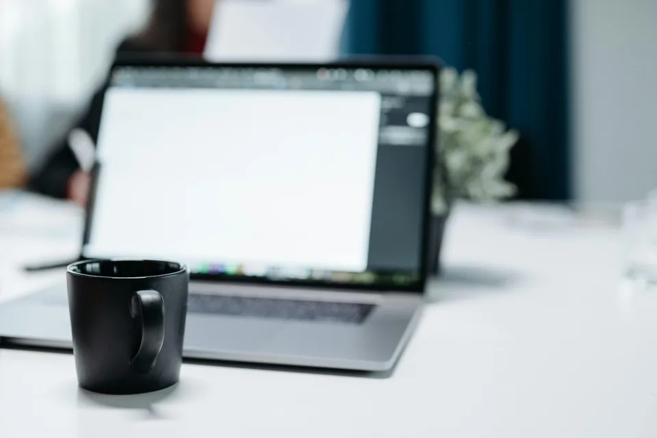 A minimal desk with a coffee mug beside a laptop in a focused work environment.