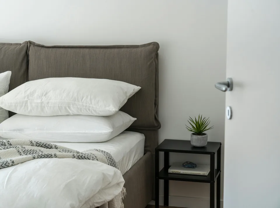 A neat bedside table beside a calm bed in a softly lit bedroom.