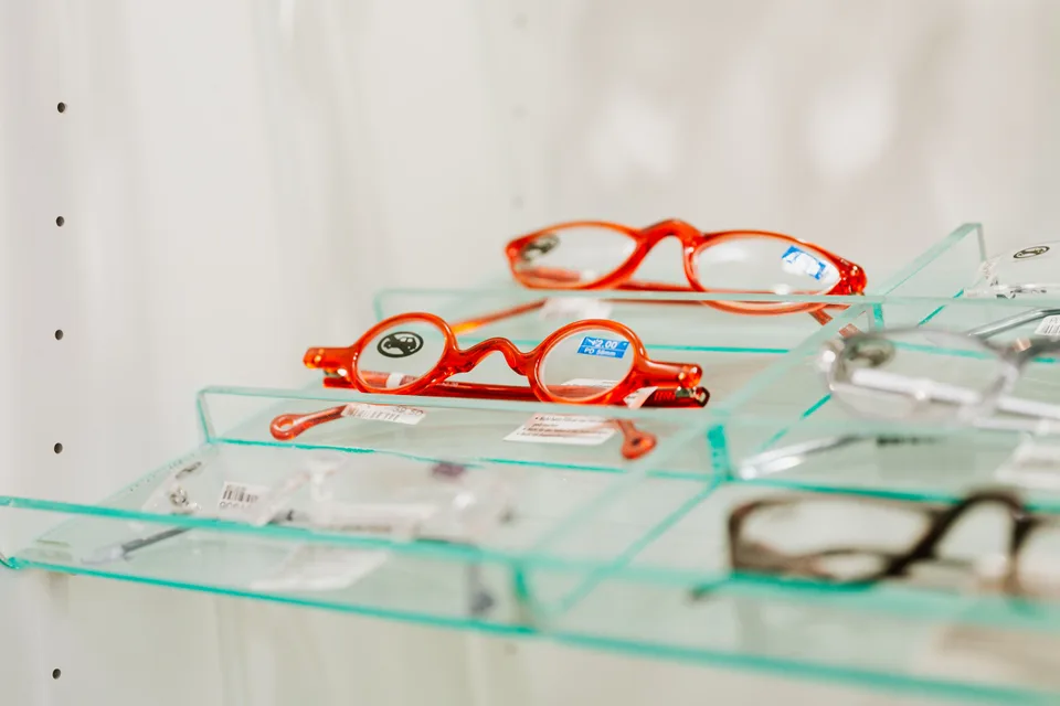 red-framed reading glasses on glass shelves in an optical shop display