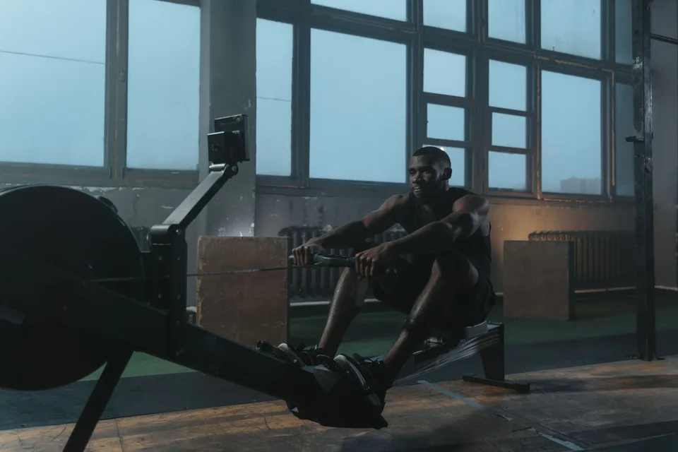 A man using a rowing machine during a workout session in a gym.