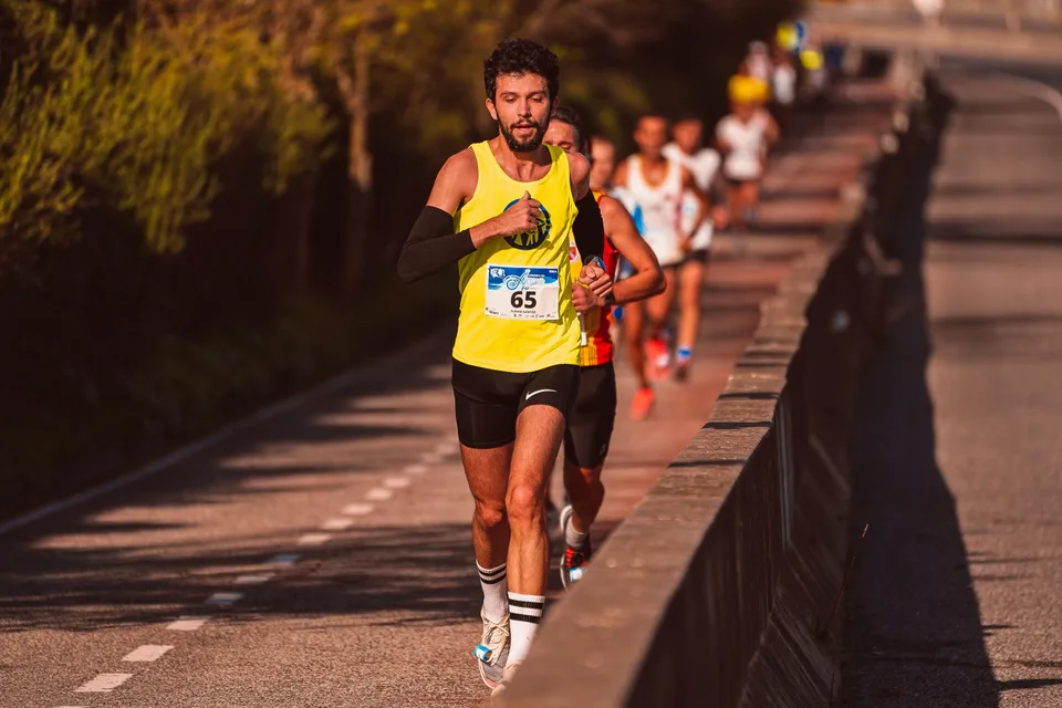 A group of marathon runners spread across a road during a race in soft daylight.
