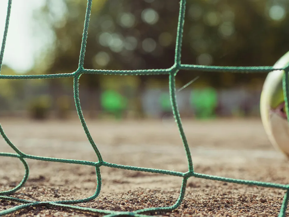 A football goal with a net against a sky background in a stadium.