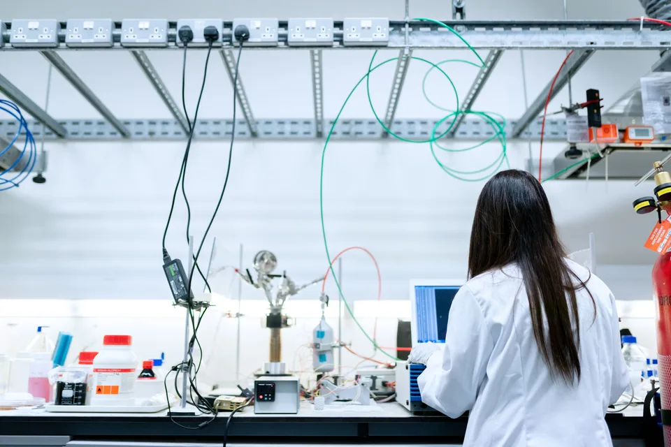 A woman in a laboratory setting conducting research, wearing safety equipment.