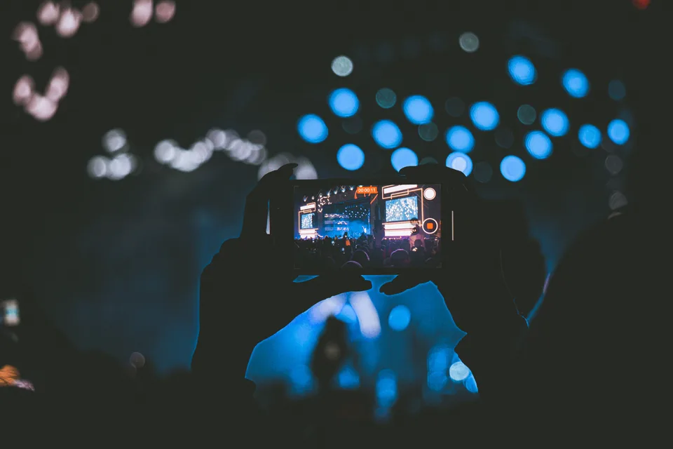 A person holding a smartphone and recording video at a live event.