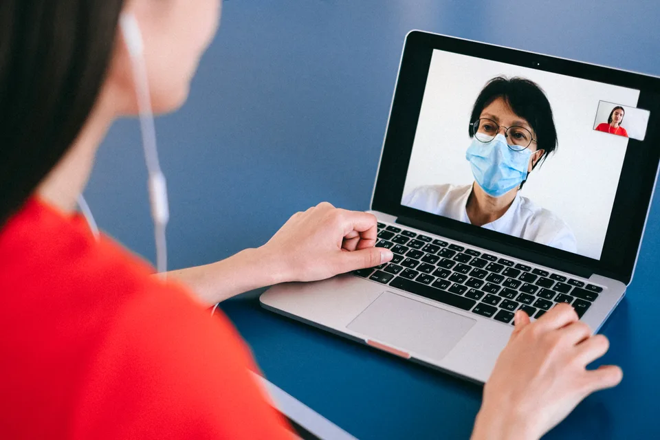A person at home on a video call from their laptop, in a casual remote-consultation setup.