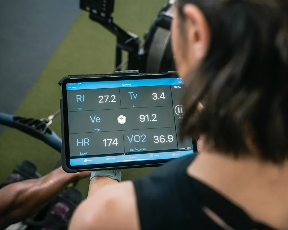 A person reviewing fitness training data on a tablet next to performance metrics.