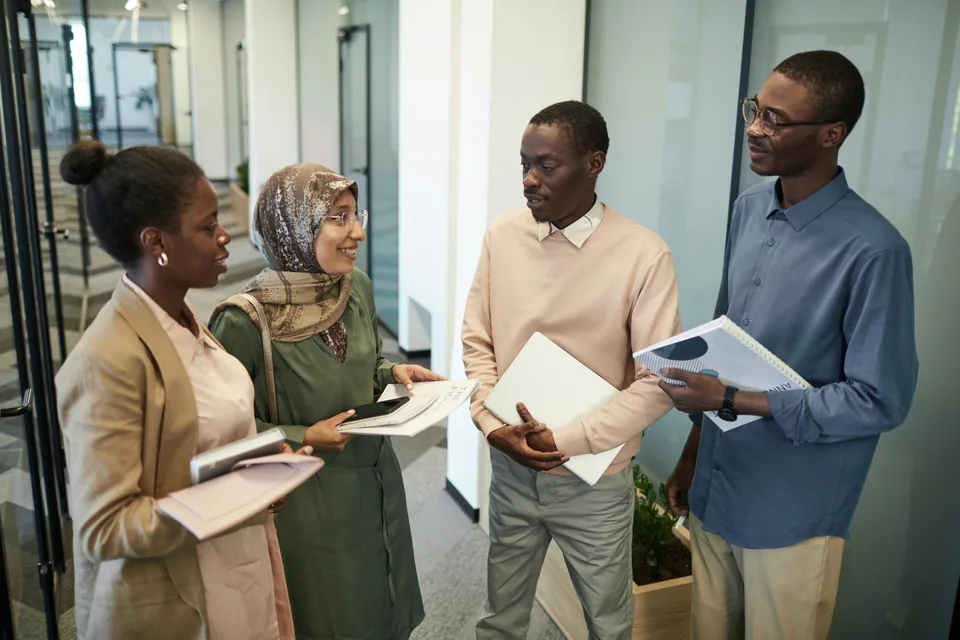 Diverse colleagues having a conversation in a modern open office setting.