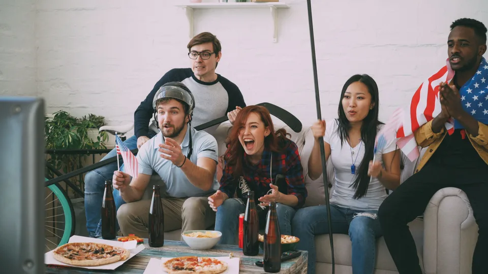 group of friends on a couch watching a sports match on television