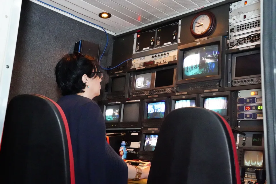 television broadcast control room with rows of monitors and a mixing desk
